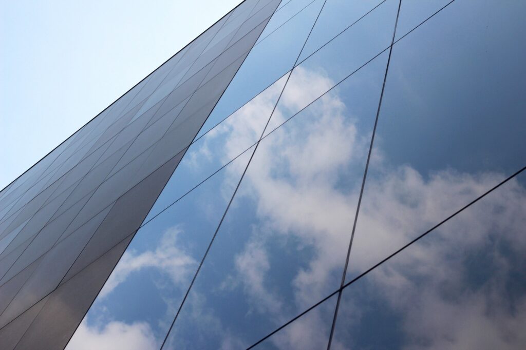 low-angle-shot-glass-high-rise-business-building-with-reflection-clouds-sky-it_181624-2641